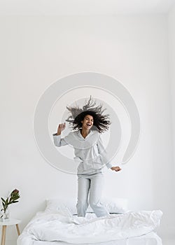 Young afro american woman jumping on bed