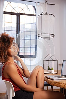 Young Afro American woman using laptop computer while sitting at table.