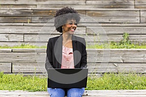 young afro American woman using laptop. Green backgrounds. Casual clothing. Lifestyles. Business.Millennial. photo