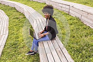 young afro American woman using laptop. Green backgrounds. Casual clothing. Lifestyles. Business. Millennial.