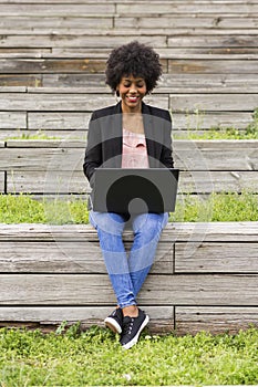 young afro American woman using laptop. Green backgrounds. Casual clothing. Lifestyles. Business.Millennial.