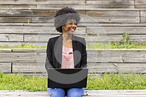 young afro American woman using laptop. Green backgrounds. Casual clothing. Lifestyles. Business.Millennial.