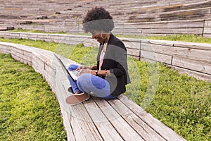 young afro American woman using laptop. Green backgrounds. Casual clothing. Lifestyles. Business. Millennial.