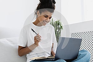 Young afro american woman watching online webinar on laptop