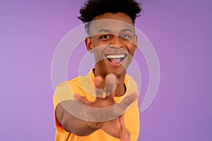 Young afro man smiling tying to catch something with his hand.