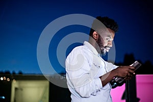 Young  Afro man on street at night using tablet computer