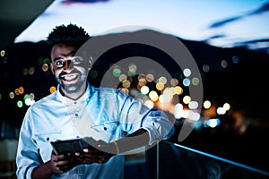 Young  Afro man on street at night using tablet computer