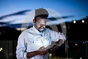 Young  Afro man on street at night using tablet computer