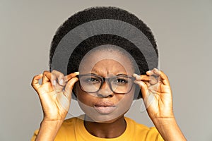 Young afro woman has poor eyesight squint eyes through glasses trying to read text. Ophthalmology