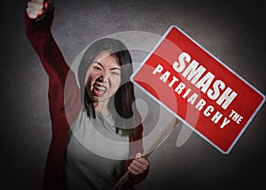 Young aggressive ultra feminist Asian Korean woman holding protest billboard with smash the patriarchy text standing for women photo