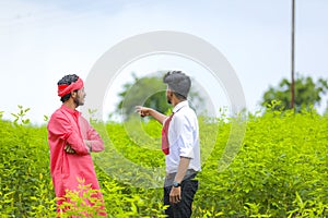 Young agronomist disscuss with farmer at green field