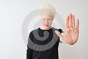 Young albino blond man wearing black t-shirt standing over isolated white background doing stop sing with palm of the hand