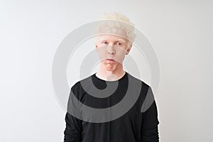 Young albino blond man wearing black t-shirt standing over isolated white background puffing cheeks with funny face