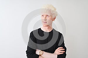 Young albino blond man wearing black t-shirt standing over isolated white background smiling looking to the side and staring away