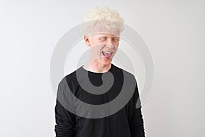 Young albino blond man wearing black t-shirt standing over isolated white background sticking tongue out happy with funny