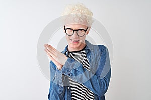 Young albino blond man wearing denim shirt and glasses over isolated white background clapping and applauding happy and joyful,