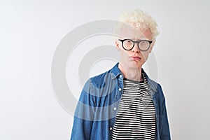 Young albino blond man wearing denim shirt and glasses over isolated white background depressed and worry for distress, crying