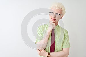 Young albino businessman wearing shirt and tie standing over isolated white background with hand on chin thinking about question,