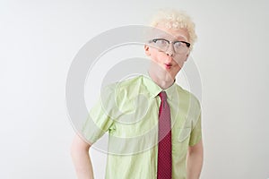 Young albino businessman wearing shirt and tie standing over isolated white background making fish face with lips, crazy and