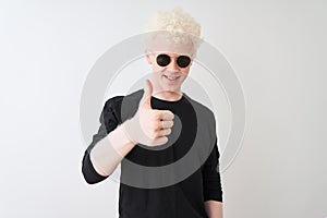 Young albino man wearing black t-shirt and sunglasess standing over isolated white background doing happy thumbs up gesture with