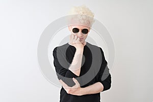 Young albino man wearing black t-shirt and sunglasess standing over isolated white background looking stressed and nervous with