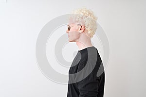 Young albino man wearing black t-shirt and sunglasess standing over isolated white background looking to side, relax profile pose