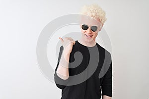 Young albino man wearing black t-shirt and sunglasess standing over isolated white background smiling with happy face looking and