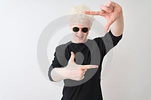 Young albino man wearing black t-shirt and sunglasess standing over isolated white background smiling making frame with hands and