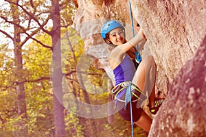 Young alpinist girl climbing on a mountain rock photo