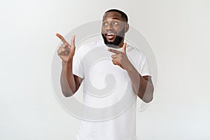 Young amazed African American pointing his finger at white background with copy space for your advertisement