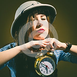 Young amazed woman in pith helmet holding alarm clock