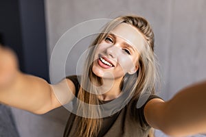 Young amazing woman make selfie on sofa indoors
