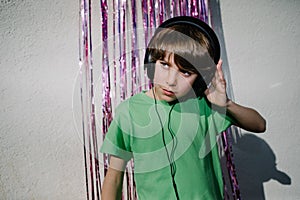 Young American boy wearing headphones near the purple confetti tapes - the concept of DJing