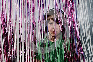 Young American boy wearing headphones near the purple confetti tapes - the concept of DJing