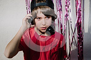 Young American boy wearing headphones near the purple confetti tapes - the concept of DJing