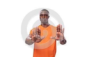 young american man dressed in orange corporate t-shirt showing refusal and disagree gesture