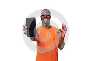 young american man experiencing joy and happiness demonstrating smartphone screen with mockup on white background with