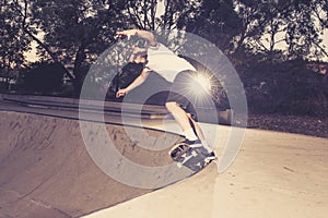 Young American man practicing radical skate board having fun enjoying tricks jumps and stunts in concrete half pipe skating track