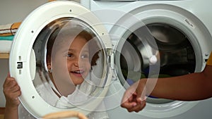 Young American mom and cute daughter having fun together in laundry room at home spbd.