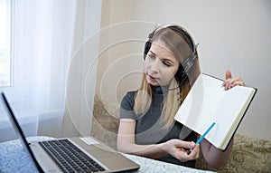young american teen girl wear headphones video calling on laptop. pretty woman student looking at computer screen watching webinar