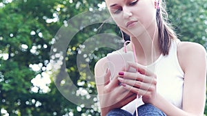 Young american teenager girl using smartphone and headphones, listen to music, park, outdoor.