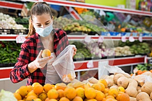 Young american woman in face mask choosing sweet tangerine