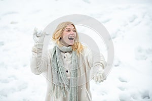 Young american woman throwing snowball at sunny day in the winter park. Girl playing with snow in park in America. Women