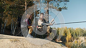 Young angler catching fish with little son sitting in chairs holding rods enjoying autumn day outside