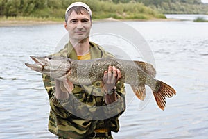 Young angler holds and showing big pike