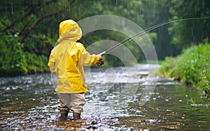 A young angler in a yellow raincoat stands resolute in a rain-soaked river, a study in concentration and persistence