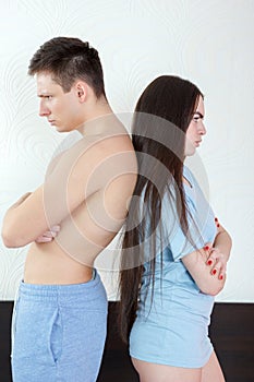 Young angry half naked couple standing back to back in bedroom