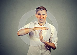 Young angry man showing time out hand gesture