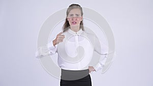 Young angry pregnant businesswoman talking and pointing at camera