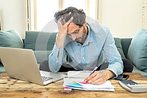 Angry man paying bills as home with laptop and calculator